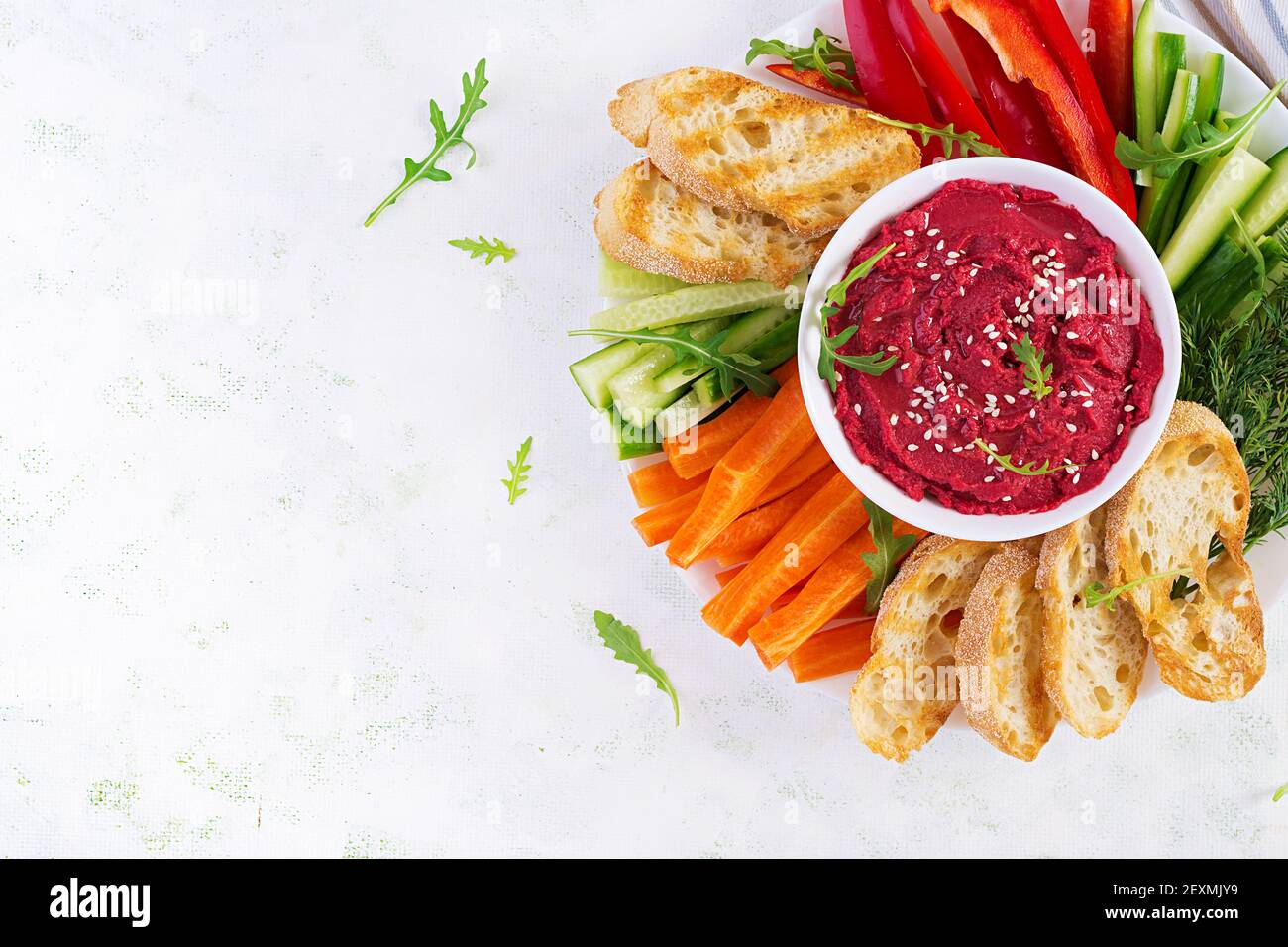 Gerösteter Rübenhummus mit Toast und Gemüse auf hellem Hintergrund. Beetroot Hummus. Draufsicht, oben, Kopierbereich Stockfoto
