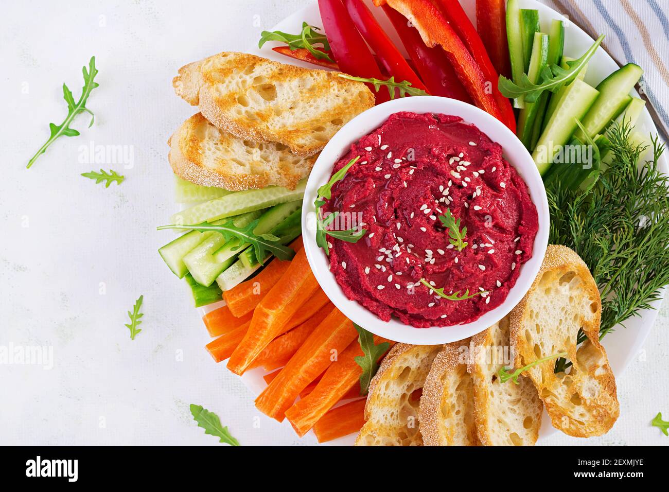 Gerösteter Rübenhummus mit Toast und Gemüse auf hellem Hintergrund. Beetroot Hummus. Draufsicht, oben, Kopierbereich Stockfoto