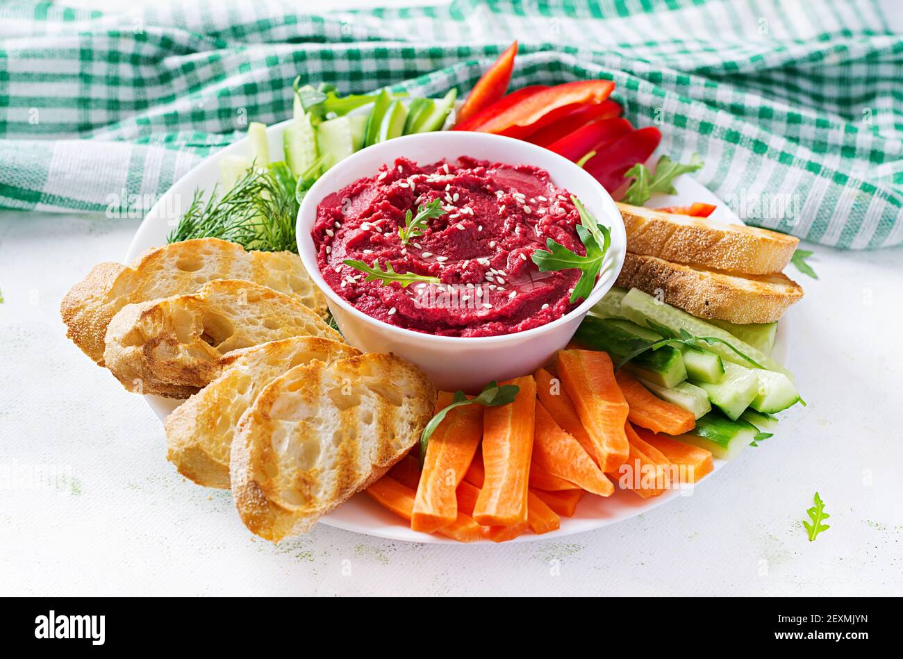 Gerösteter Rübenhummus mit Toast und Gemüse auf hellem Hintergrund. Beetroot Hummus. Stockfoto
