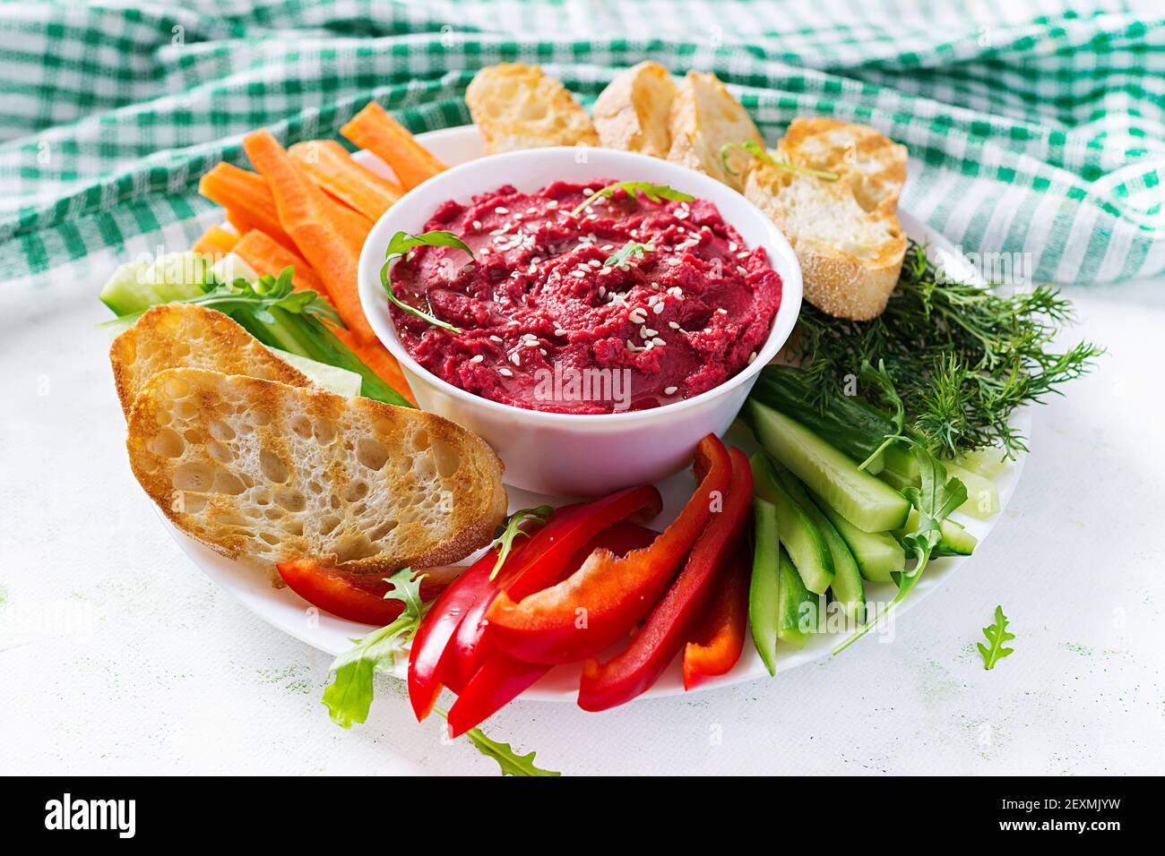 Gerösteter Rübenhummus mit Toast und Gemüse auf hellem Hintergrund. Beetroot Hummus. Stockfoto