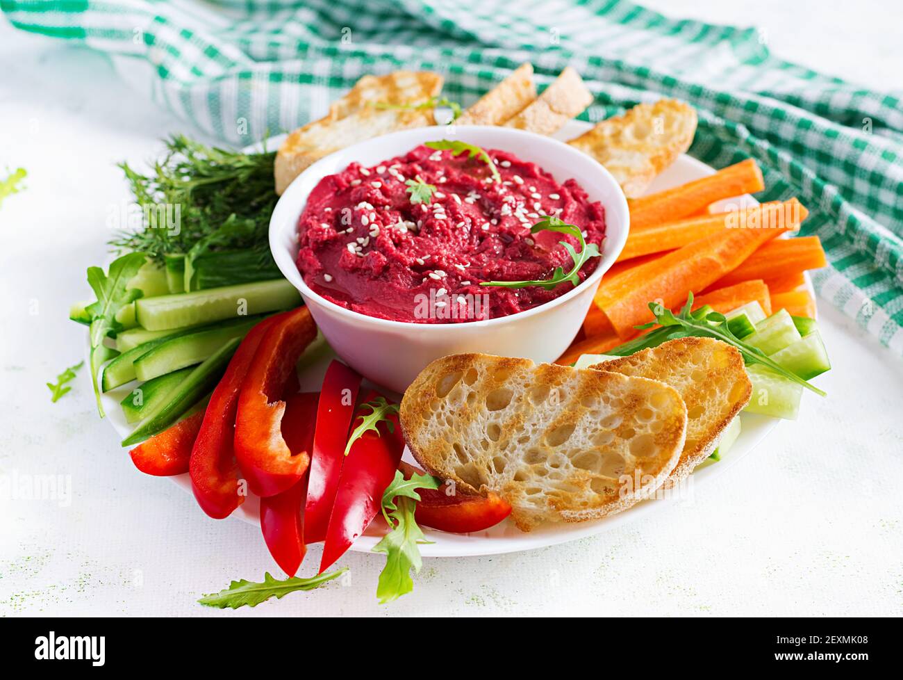 Gerösteter Rübenhummus mit Toast und Gemüse auf hellem Hintergrund. Beetroot Hummus. Stockfoto
