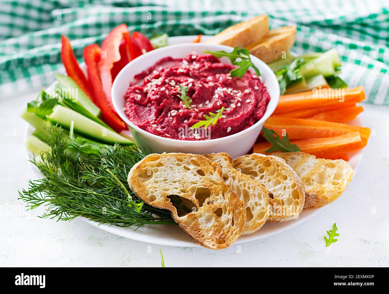 Gerösteter Rübenhummus mit Toast und Gemüse auf hellem Hintergrund. Beetroot Hummus. Stockfoto