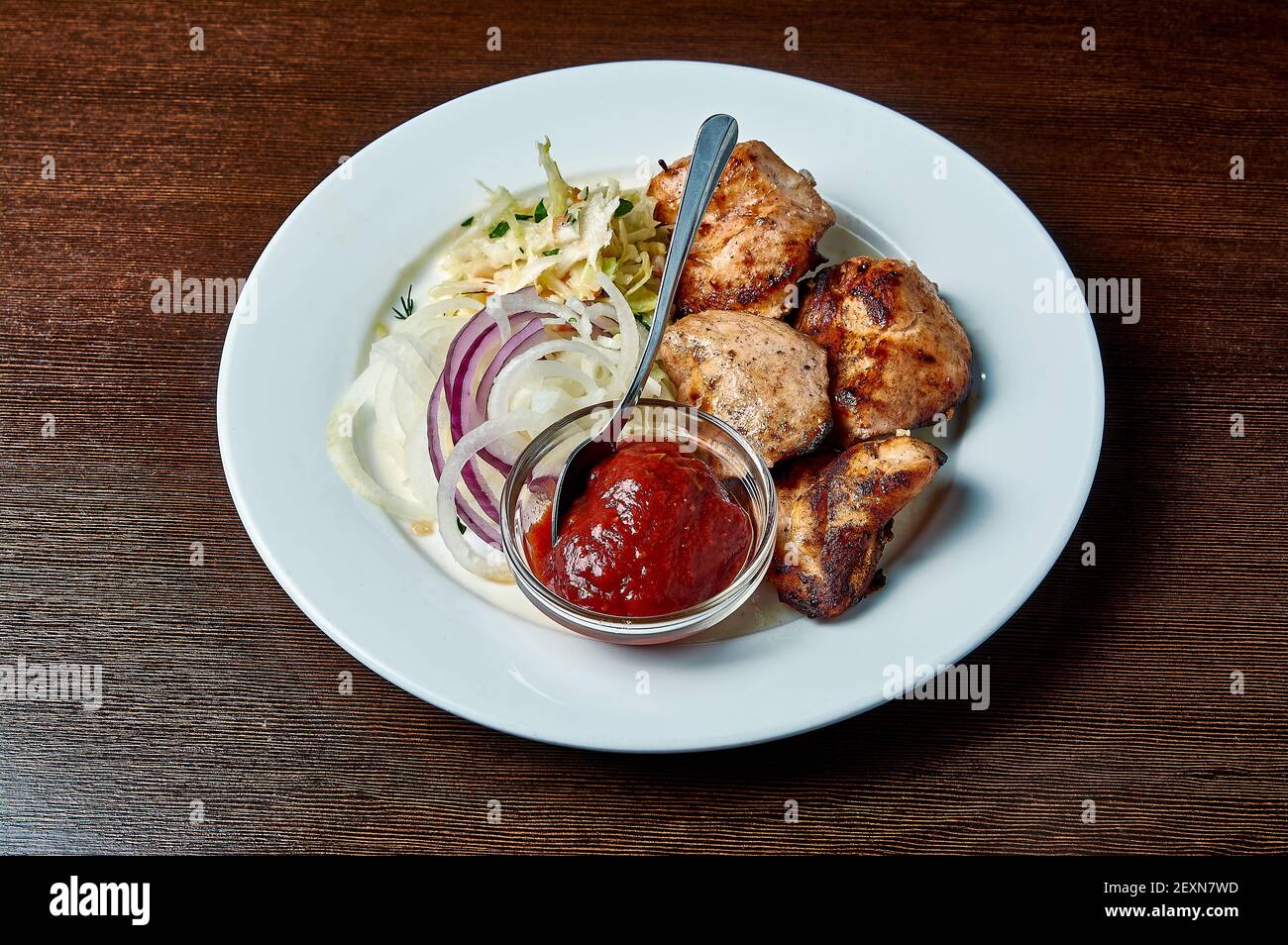 shish Kebab mit Salat und Ketchup auf einem Teller auf Ein dunkler Hintergrund Stockfoto