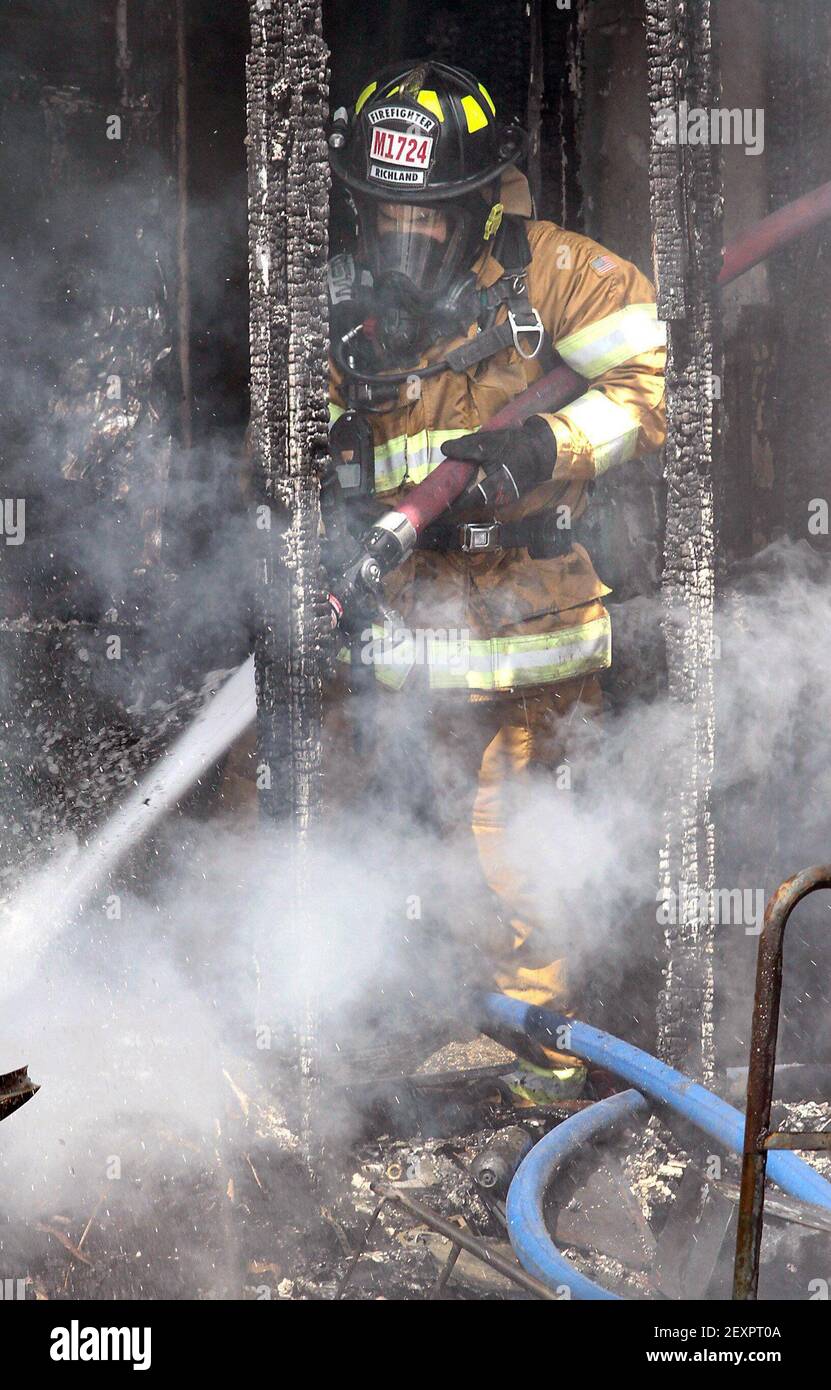 Ein Richland Feuerwehrmann sprüht schwelende Bereiche Dienstag 15. April 2014 auf der hinteren Veranda eines Hauses bei 115 N. Seventh Ave. In Pasco, Wash. Eine Person war zu Hause, aber nicht verletzt wurde, sagten Beamte. Das Feuer beschädigte das Innere, den Dachboden und eine nahe gelegene Garage. Fünfunddreißig Feuerwehrleute aus Pasco, Kennewick, Richland und Walla Walla Fire District 5 halfen bei der Bekämpfung des Feuers. (Foto von Bob Brawdy/Tri-City Herald/MCT/Sipa USA) Stockfoto