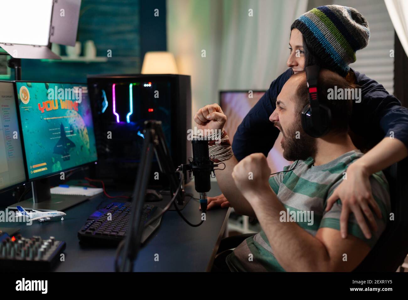 Streamer paar gewinnen online Weltraum-Shooter-Wettbewerb mit professionellen Headset, Mikrofon, Tastatur. Gamer spielen Online-Videospiele mit neuen Grafiken auf leistungsstarken Computer Stockfoto