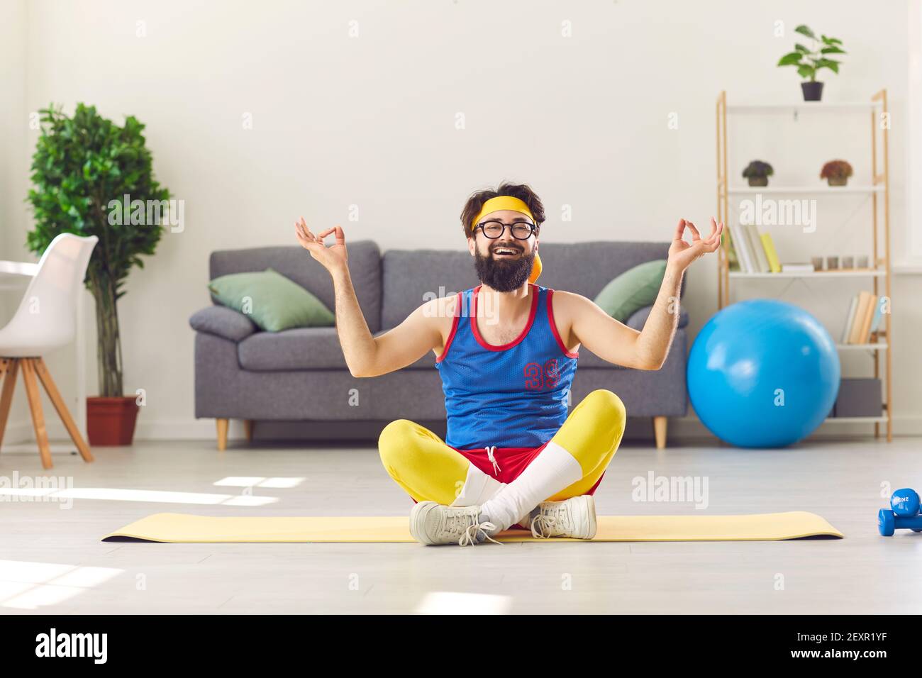 Lustige glückliche Mann in Retro-Sportbekleidung sitzen in easy Yoga Pose und Meditieren lernen Stockfoto