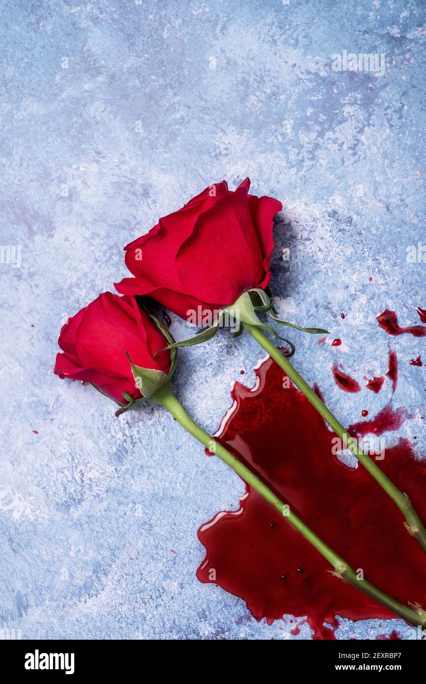 Rote Rosen und Blut auf einem blauen texturierten Hintergrund mit Platz für Text und Text Stockfoto