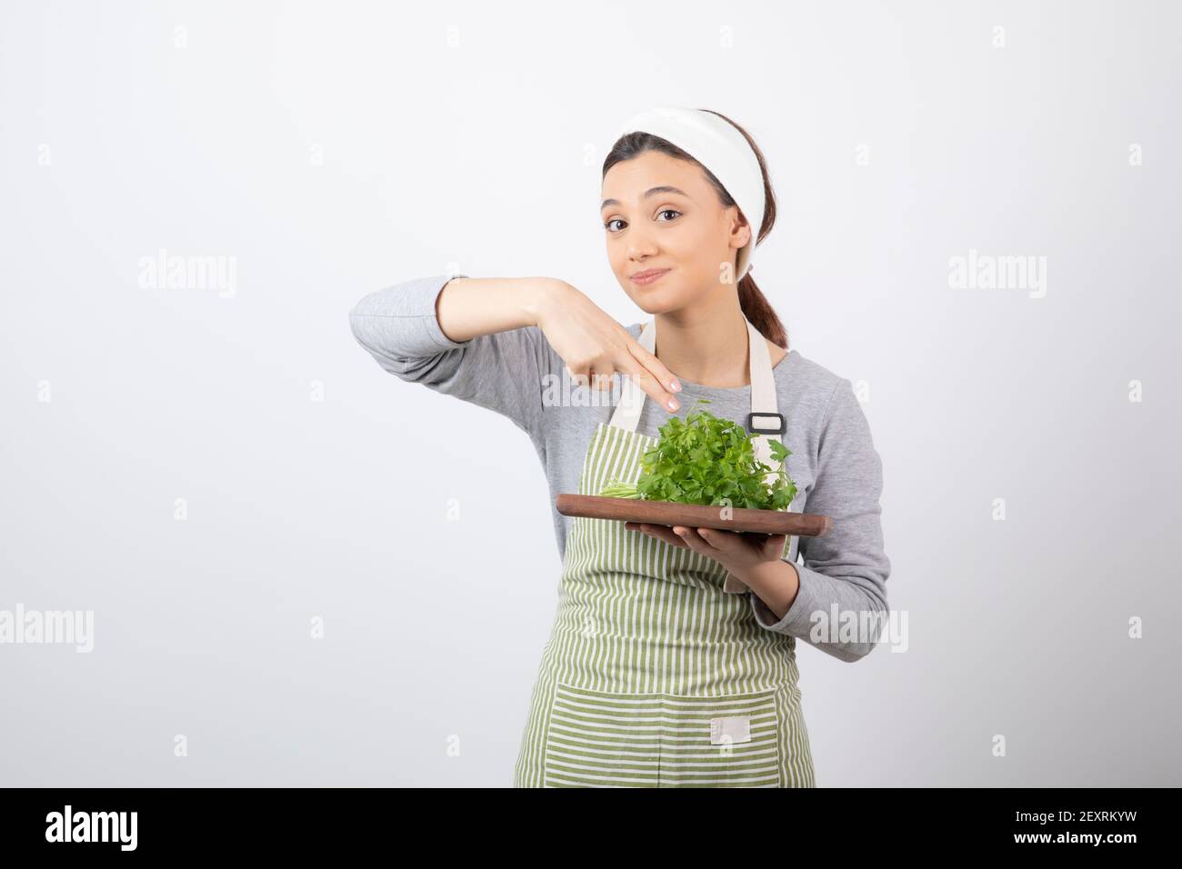 Porträt einer hübschen niedlichen Frau mit einem Holzbrett Mit frischer Petersilie Stockfoto