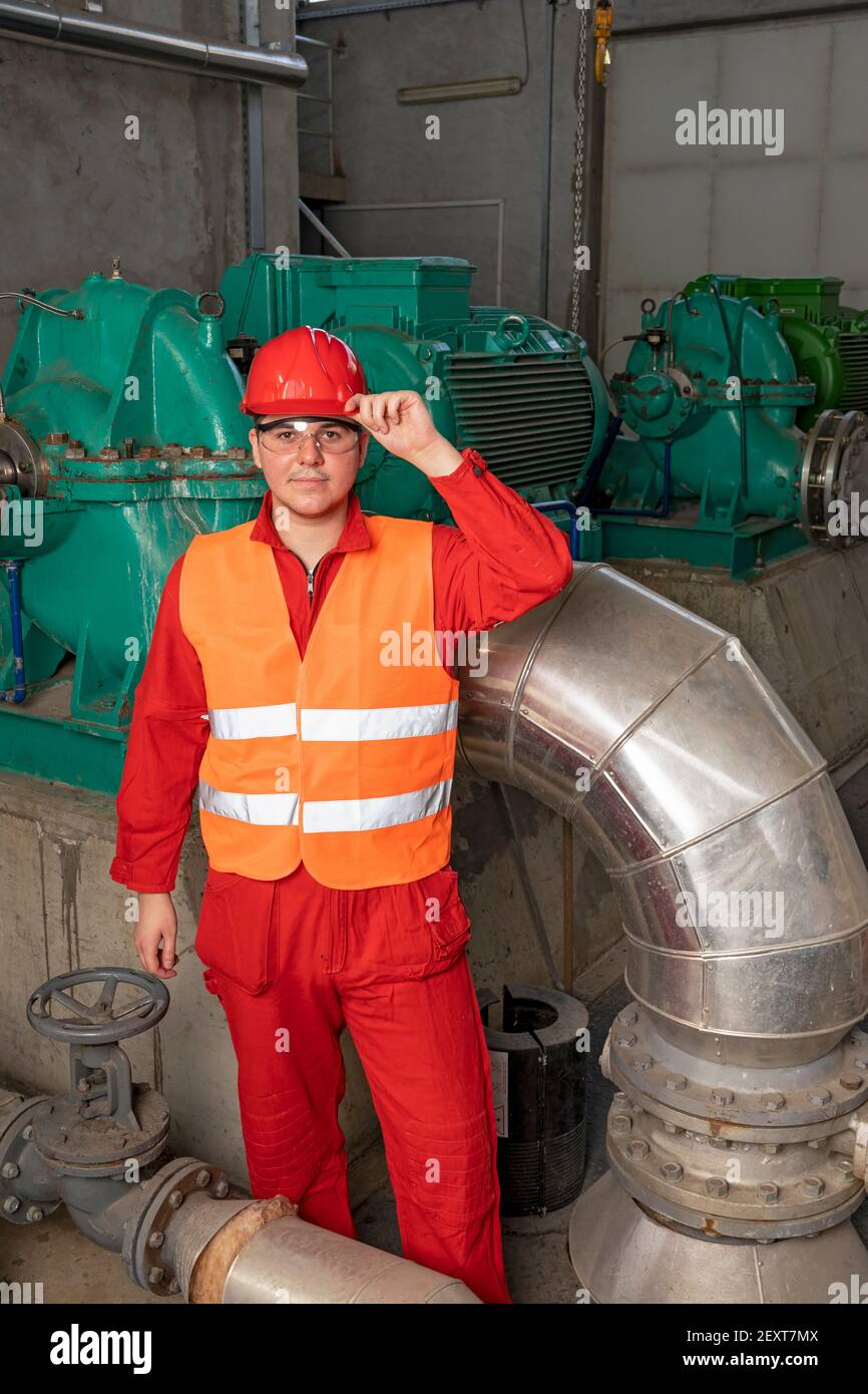 Porträt eines jungen Arbeiters im Fernwärmekraftwerk. Arbeiter in persönlicher Schutzausrüstung im industriellen Innenraum. Stockfoto