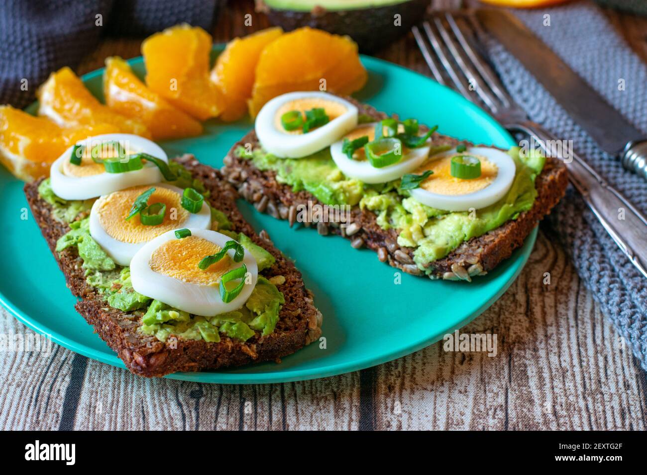 Vegetarische Mahlzeit mit offenem Sandwich mit Avocado und gekocht Eierscheiben serviert mit frisch geschälten Orangen auf einem Klima Freundlicher Bambusteller Stockfoto