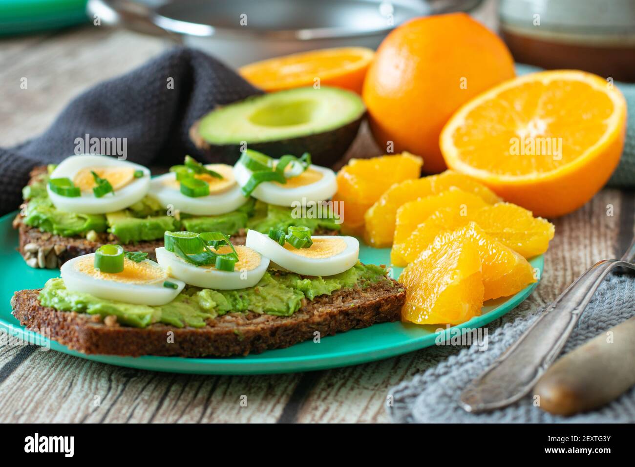 Trainingsmenü mit Ei-Avocado-Sandwich serviert mit frisch geschälten Orangen. Post- und Pre-Workout-Mahlzeit auf einem klimafreundlichen Bambusblech Stockfoto