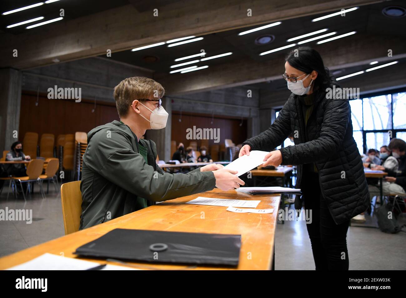 05. März 2021, Bayern, München: Gabriel (18), Schüler der Oberschule am Werner-von-Siemens-Gymnasium, erhält seinen Zwischenbericht von seinem Lehrer in der Aula der Schule. Aufgrund des laufenden Fernlernens werden die Zwischenberichte derzeit von vielen Schulen in Bayern verschickt, teilweise ausgehändigt und einige Ausnahmen sind möglich. Foto: Tobias Hase/dpa Stockfoto