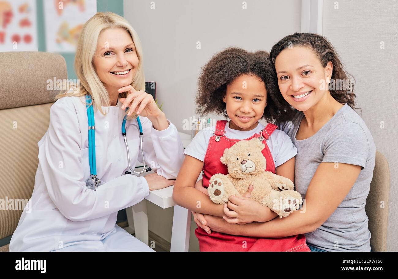 Glückliche afroamerikanische Mutter mit ihrer Tochter beim Besuch eines Kinderarztes. Gesundheit von Kindern Stockfoto