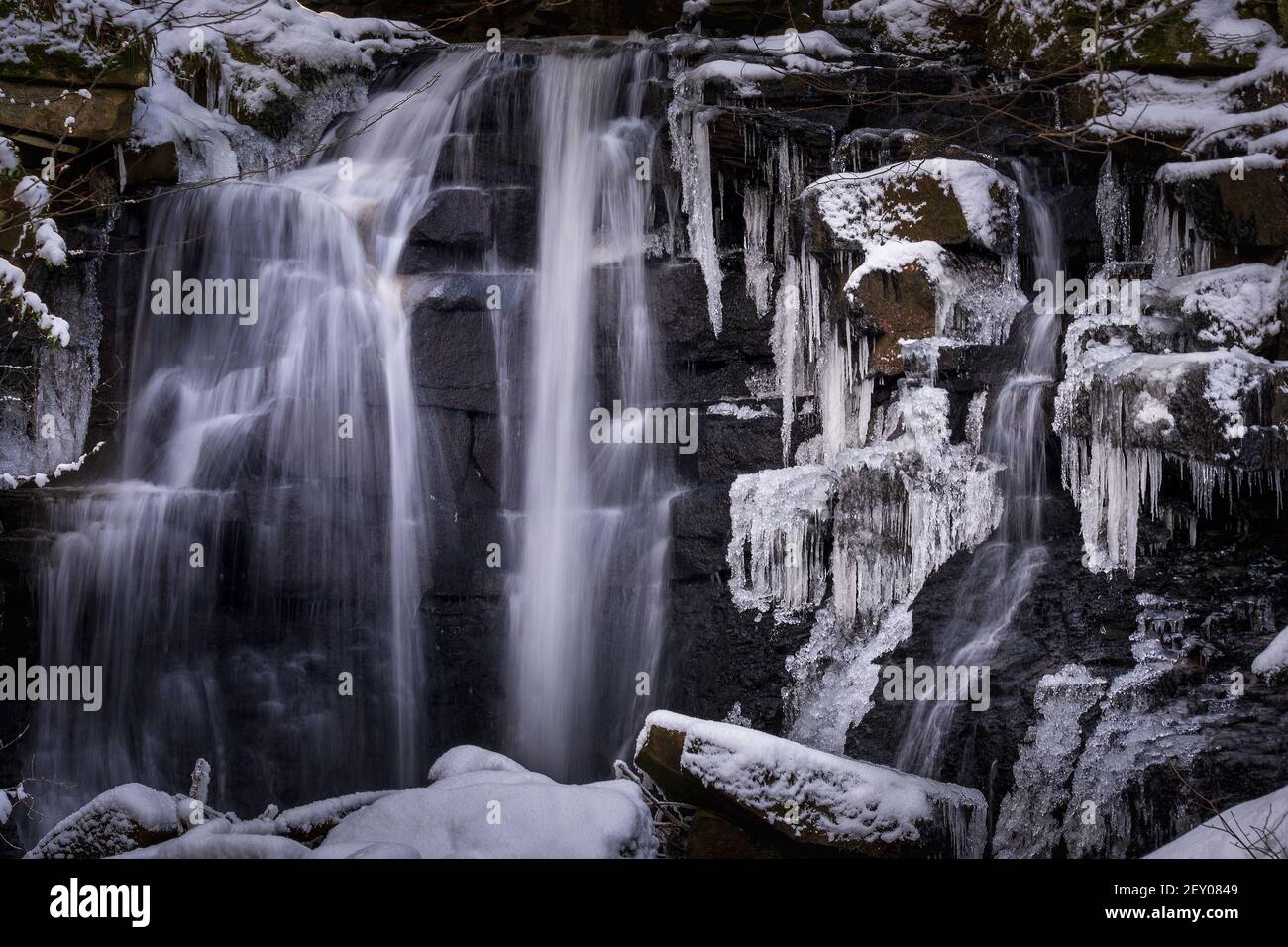 Gefrorener Wasserfall mit eisbedeckten Felsen und Eiszapfen. Wharnley Burn County Durham im Winter. Stockfoto