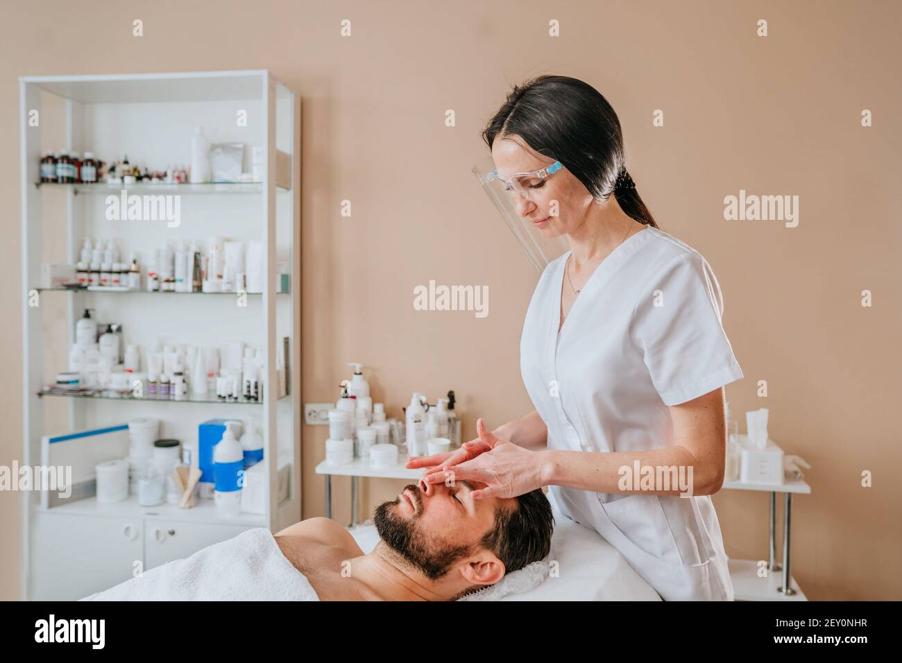 Ästhetiker oder facialist gibt eine entspannende Gesichtsmassage zu einem Mann Stockfoto