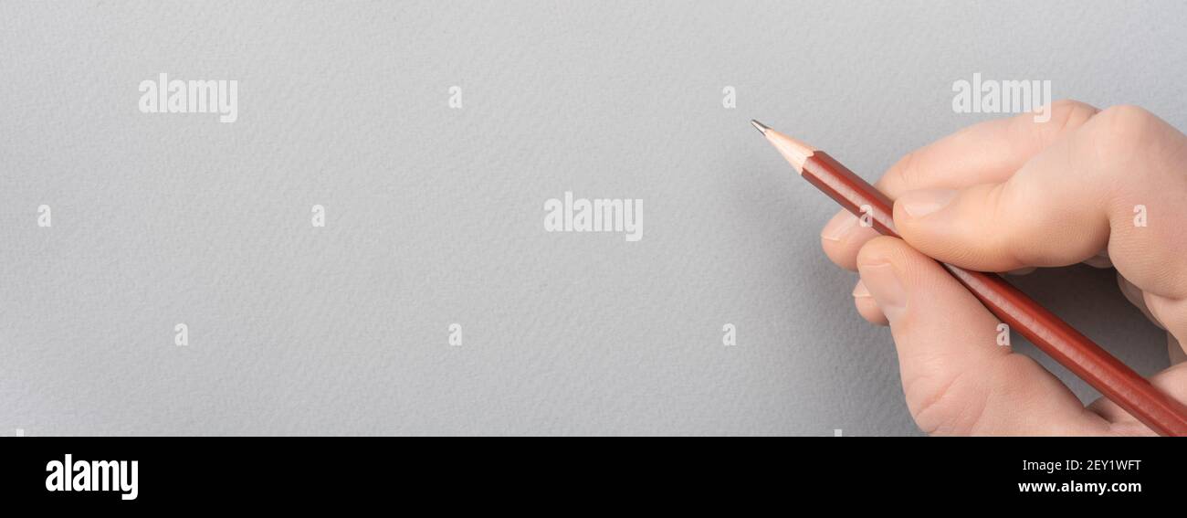 Schreiben auf grauem Papier mit Bleistift. Hand mit Bleistift schreiben etwas auf grauem Papier. Menschliche Hand Zeichnung mit Bleistift auf leerem Papier Vorlage. Raum f Stockfoto