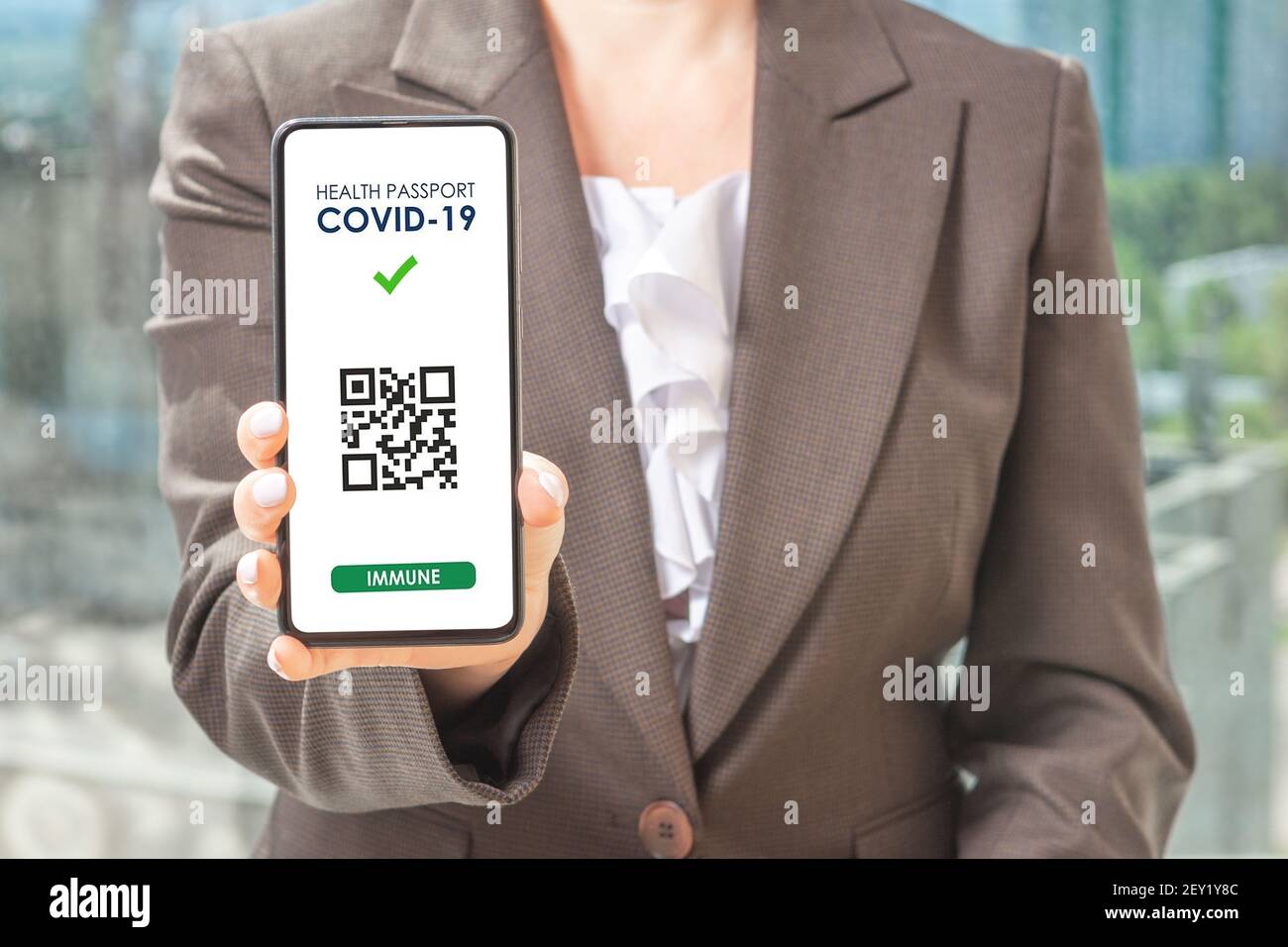 Covid-19 Health Pass App Konzept auf Smartphone. Frau Hodling Telefon. Frau hält Smartphone mit einem QR-Code digitale Illustration von Covid-19 Gesundheit Stockfoto