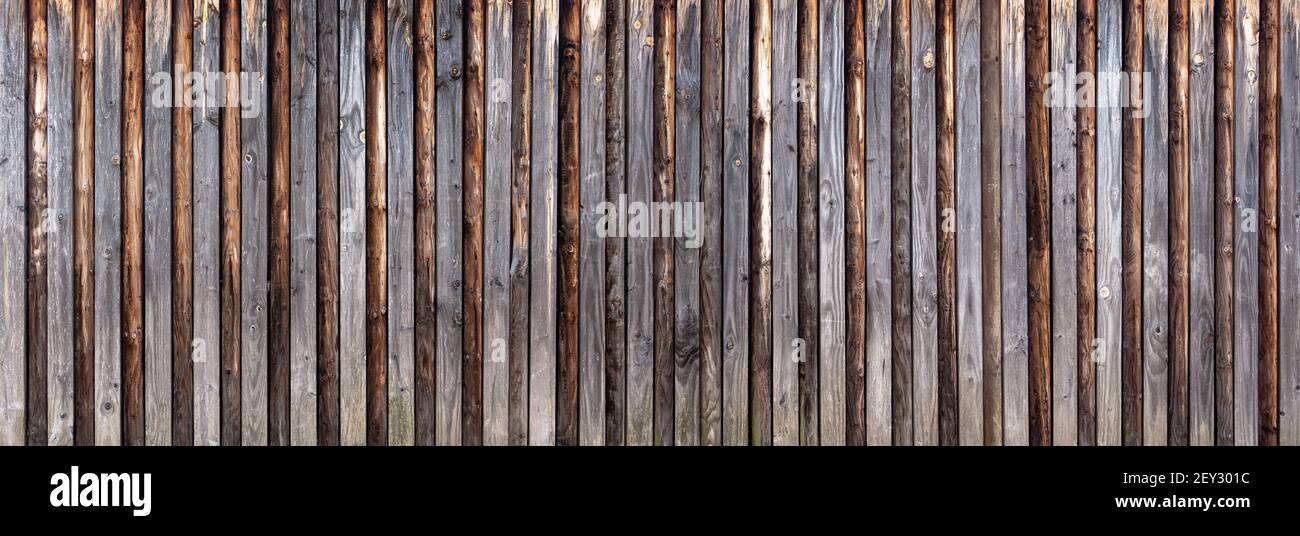 Holzwand aus vertikalen Brettern mit angebrachten Rundhölzern Stockfoto