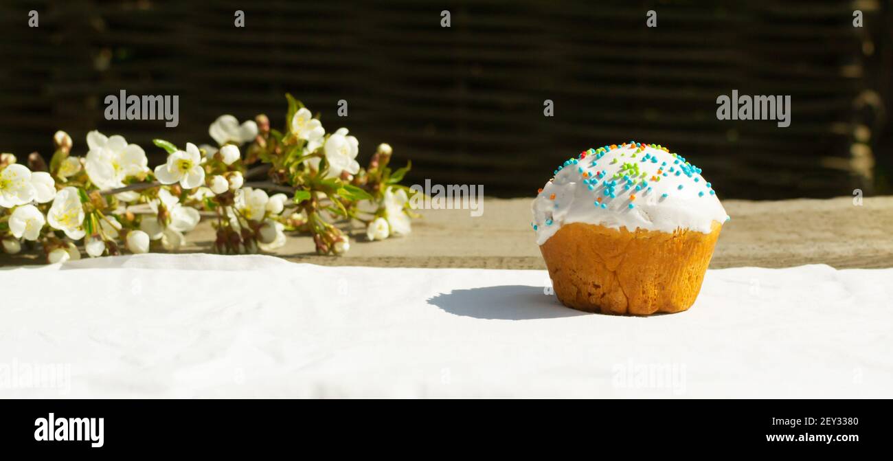 Der Osterkuchen auf der weißen Tischdecke mit dem Zweig des blühenden Apfelbaumes. Frühlingsurlaub. Horizontale Ausrichtung. Speicherplatz kopieren. Stockfoto