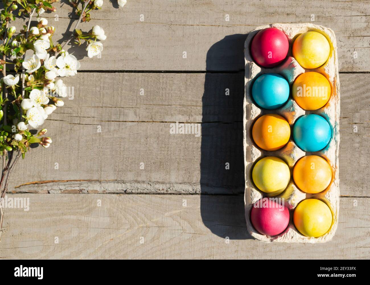 Ostern bunte Eier mit einem Zweig eines blühenden Apfelbaums auf einem hölzernen Hintergrund. Christliches Urlaubskonzept. Horizontale Ausrichtung. Speicherplatz kopieren. Stockfoto