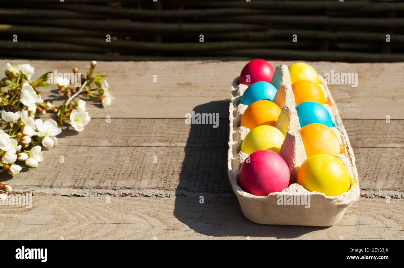 Ostern bunte Eier mit einem Zweig eines blühenden Apfelbaums auf einem hölzernen Hintergrund. Christliches Urlaubskonzept. Horizontale Ausrichtung. Speicherplatz kopieren. Stockfoto