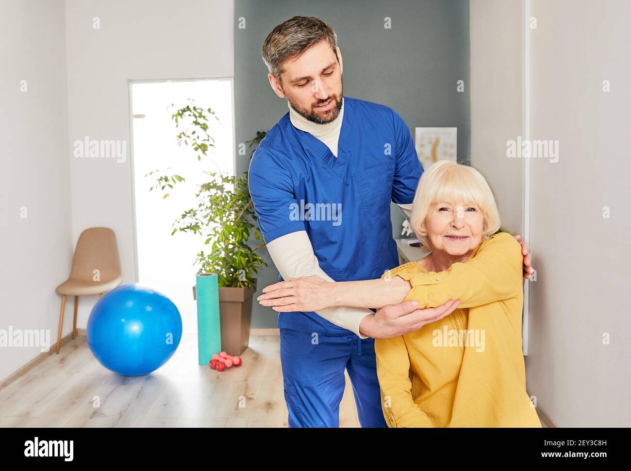 Arthritis eines Ellenbogengelenks bei einer älteren Patientin in einem Rehabilitationszentrum. Chiropraktiker hilft bei der Durchführung von Hand Gesundheit Erholung Übungen Stockfoto