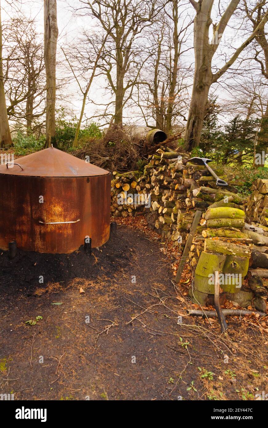 Ein traditioneller Holzkohlebrenner Ofen oder Ofen und ein Stapel Von Baumstämmen in einer Waldlichtung in Nordwales für Herstellung von traditionellen Holzkohle Brennstoff Stockfoto