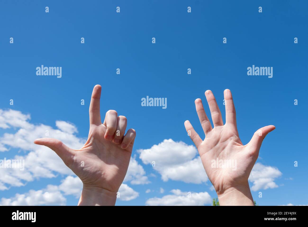 Geste Nahaufnahme der Hand einer Frau zeigt eine offene Handfläche und zwei Finger oben isoliert auf einem blauen Himmel Hintergrund mit Wolken, Nummer sieben ist Zeichen languag Stockfoto