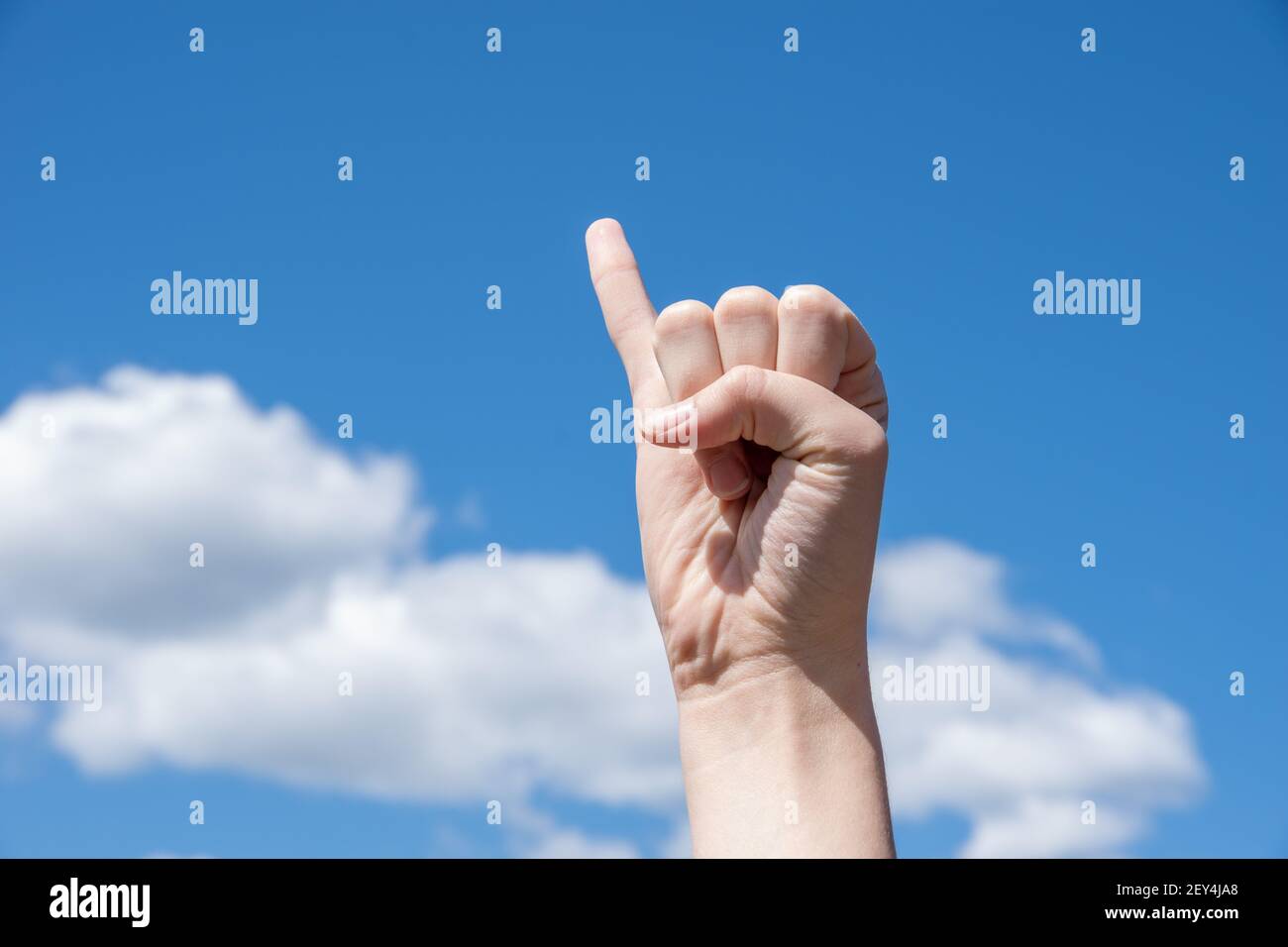 Hand in eine Faust geballt mit einem ausgestreckten kleinen Finger auf einem blauen Hintergrund. Hand zeigt kleinen Finger, Konzept der vielversprechenden Hand oder reconciliatio Stockfoto