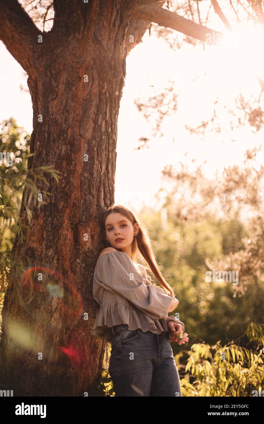 Teenager-Mädchen stehen von Kiefer Stamm im Wald während Sommer Stockfoto