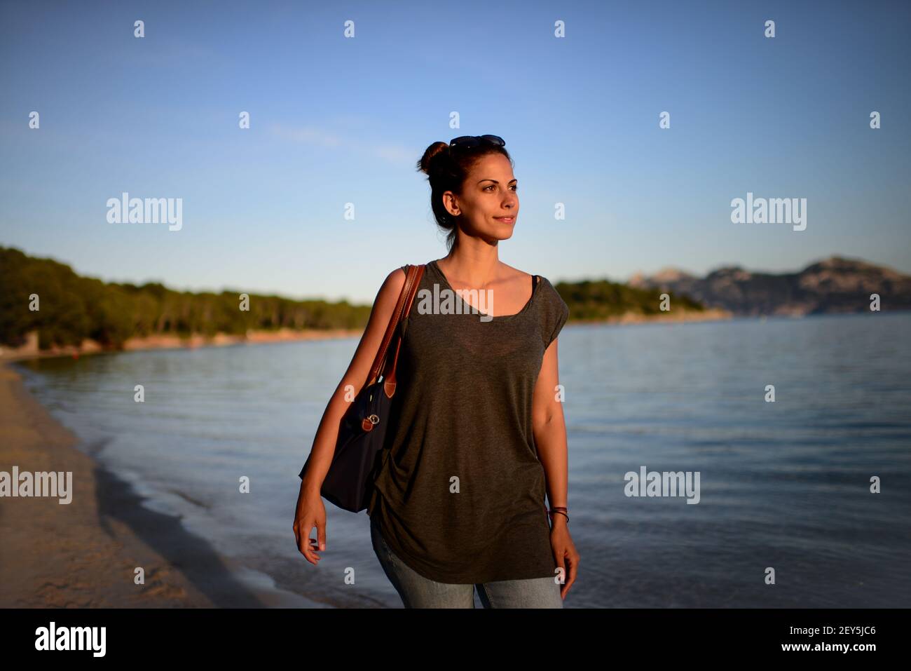 Beschauliche junge Frau geht am Strand spazieren Stockfoto