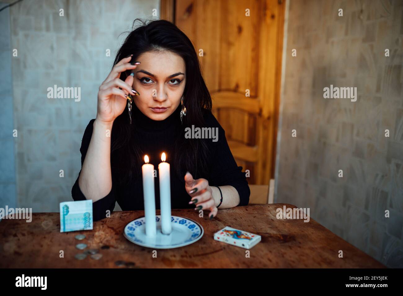 Das Mädchen erraten auf einer brennenden Kerze und Karten, die Zukunft und das Schicksal vorherzusagen Stockfoto