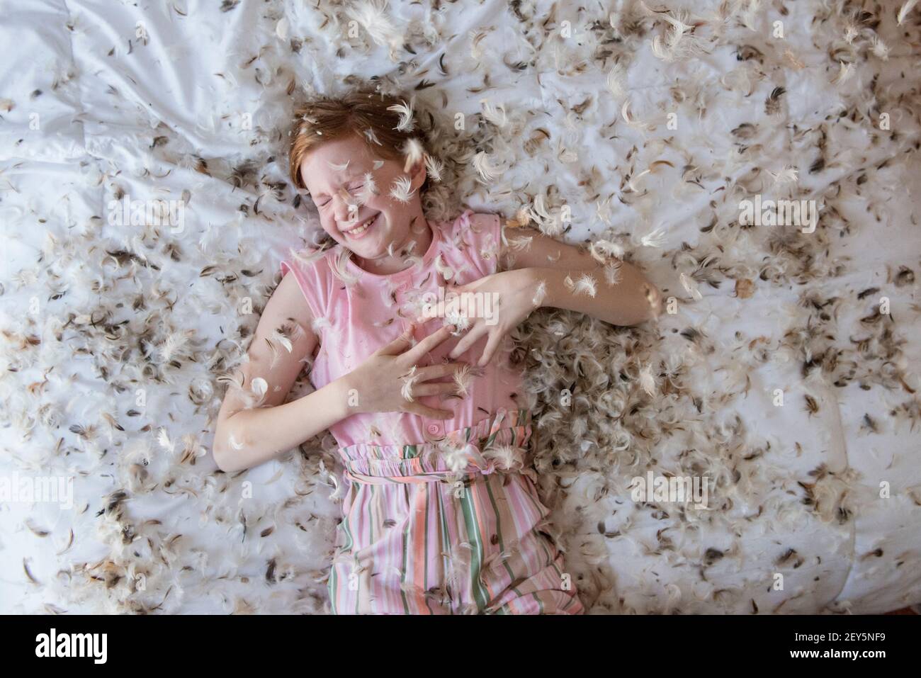 Junge rothaarige Mädchen lag auf dem Bett während einer Feder Kissen Kampf. Stockfoto