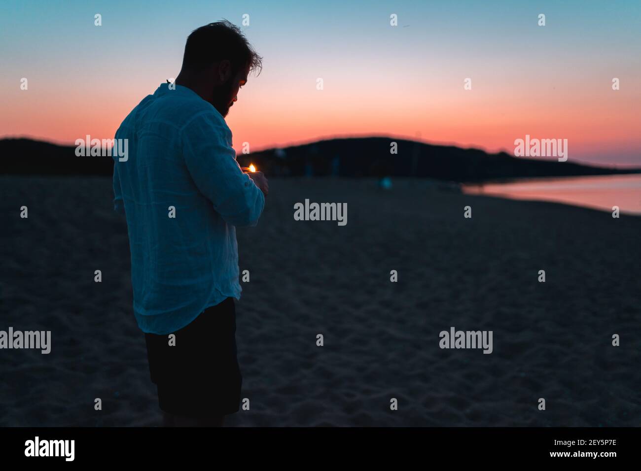 Silhouette von Männern am Strand leichte Zigaretten bei Sonnenuntergang Während der goldenen Stunde Stockfoto