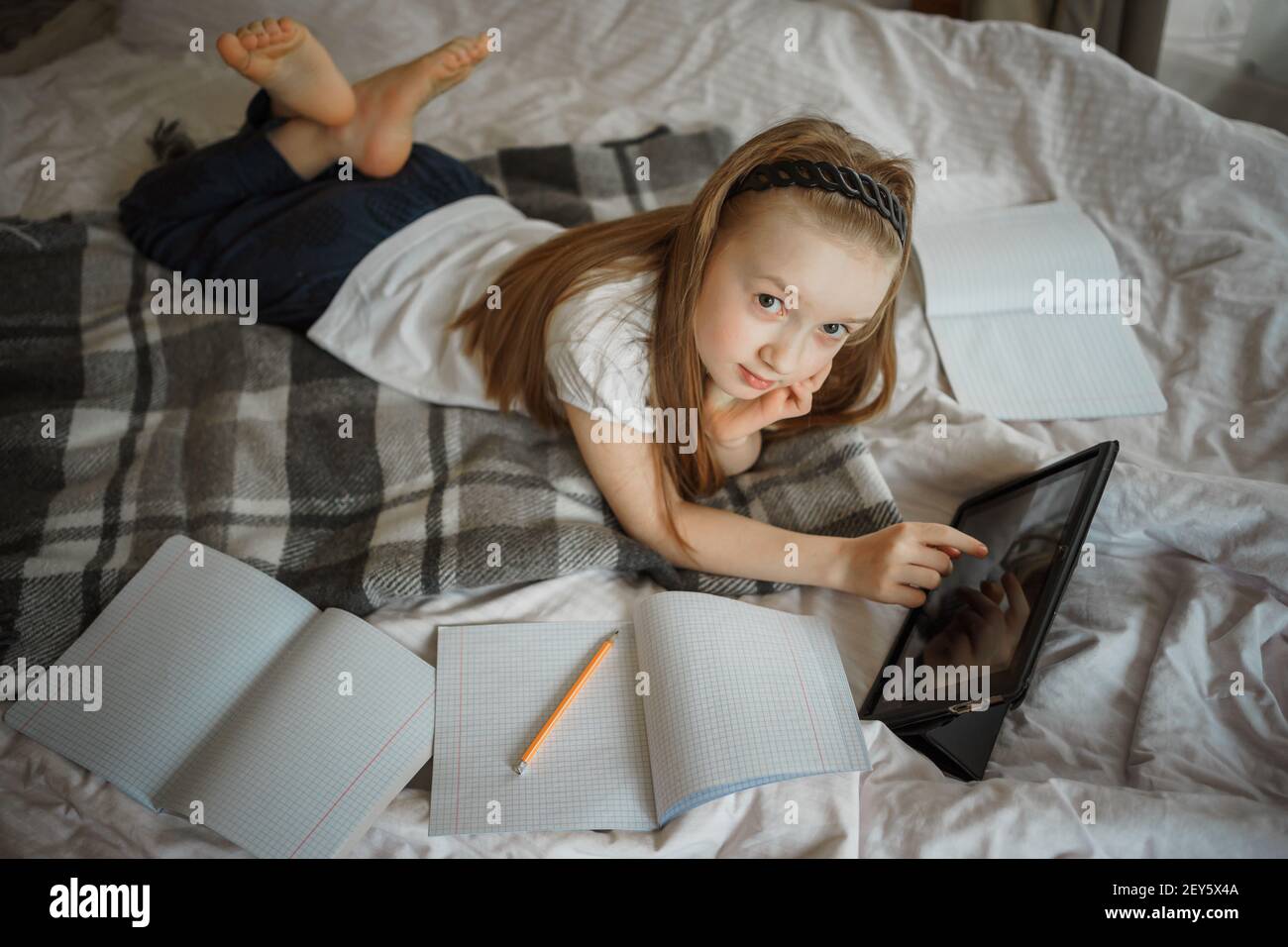 Mädchen liegt auf dem Bett, umgeben von Notizbüchern Stockfoto