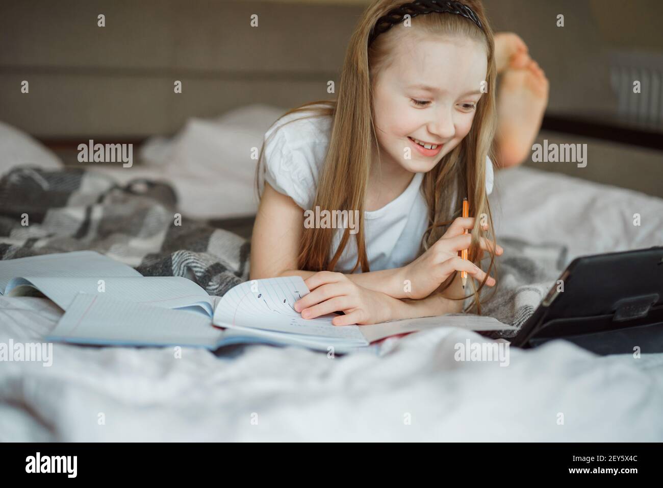 Mädchen liegt auf dem Bett, umgeben von Notizbüchern Stockfoto