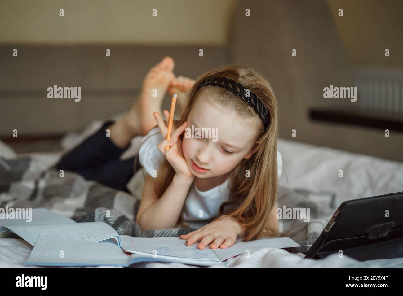 Mädchen liegt auf dem Bett, umgeben von Notizbüchern Stockfoto