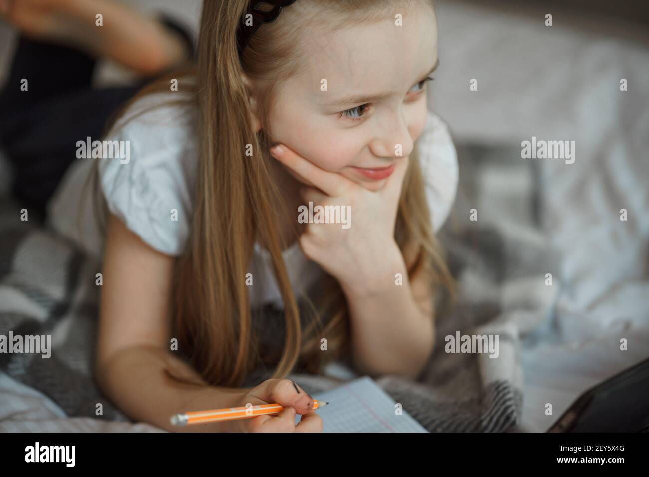 Mädchen liegt auf dem Bett, umgeben von Notizbüchern Stockfoto