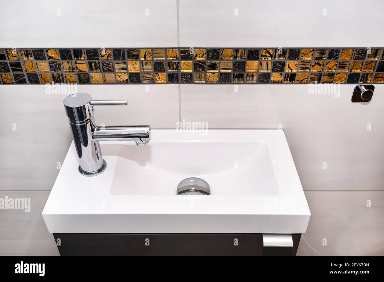 Ein kleines rechteckiges Waschbecken mit einem silbernen Wasserhahn auf der  linken Seite in einem gefliesten Badezimmer Stockfotografie - Alamy