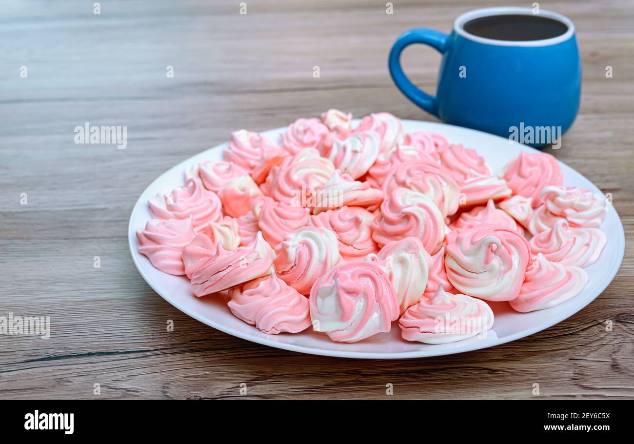 Leckere luftige zweifarbige Baiser auf einem Teller mit einer Tasse Kaffee. Stockfoto