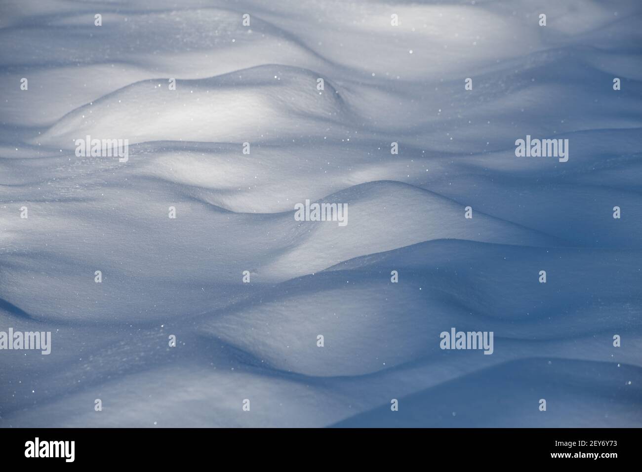 Nahaufnahme von Schneehöden nach Neuschnee fallen im Winter kalte Temperaturen Sonne scheint auf Neuschnekristalle Schatten hinter Schneeverwehungen im Feld Stockfoto