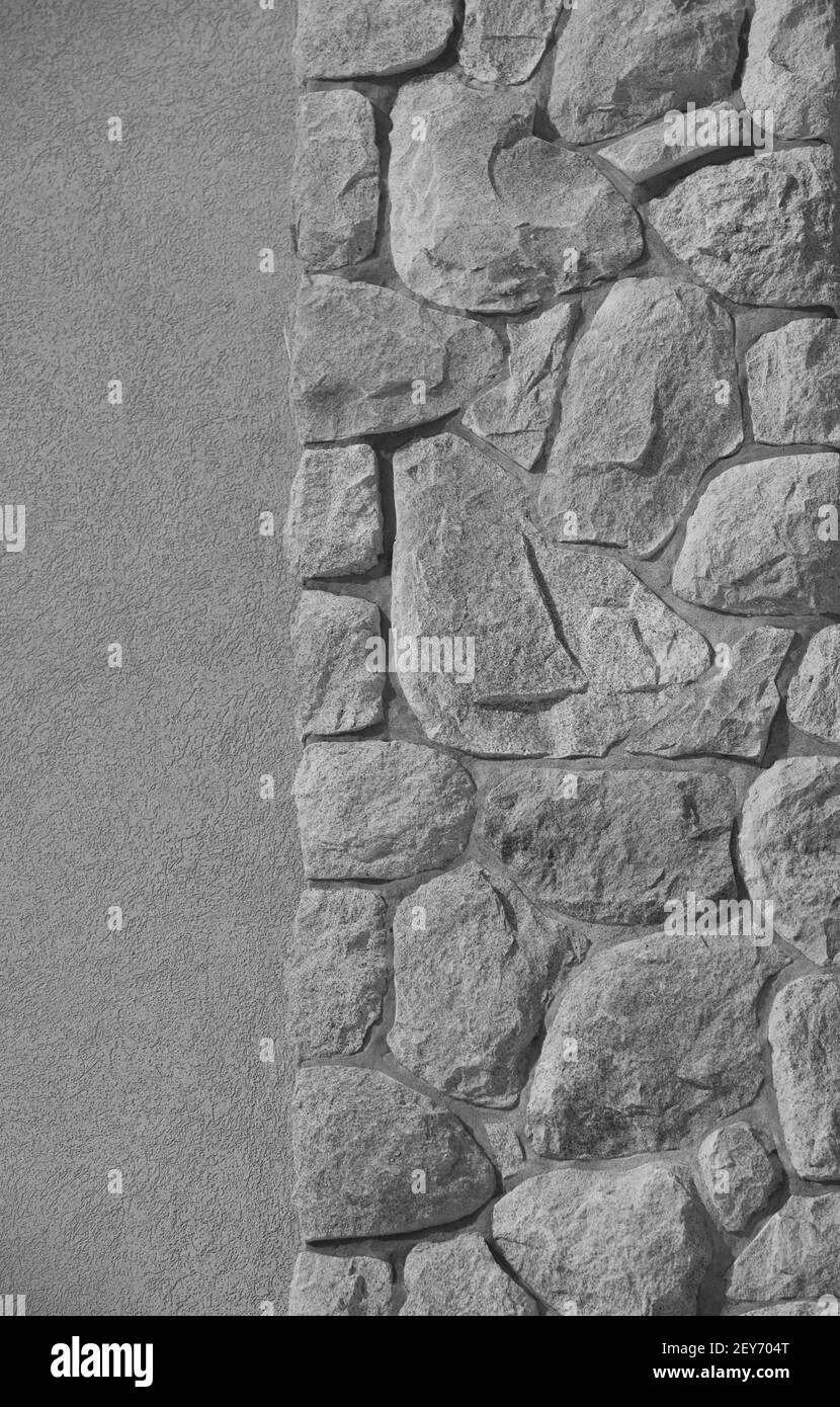 Teil des äußeren Steinkamins auf der äußeren Betonwand des Hauses Nahaufnahme Steine zufällig von Maurer unregelmäßig geformten Felsen platziert Wie Gesicht leeren Raum Stockfoto