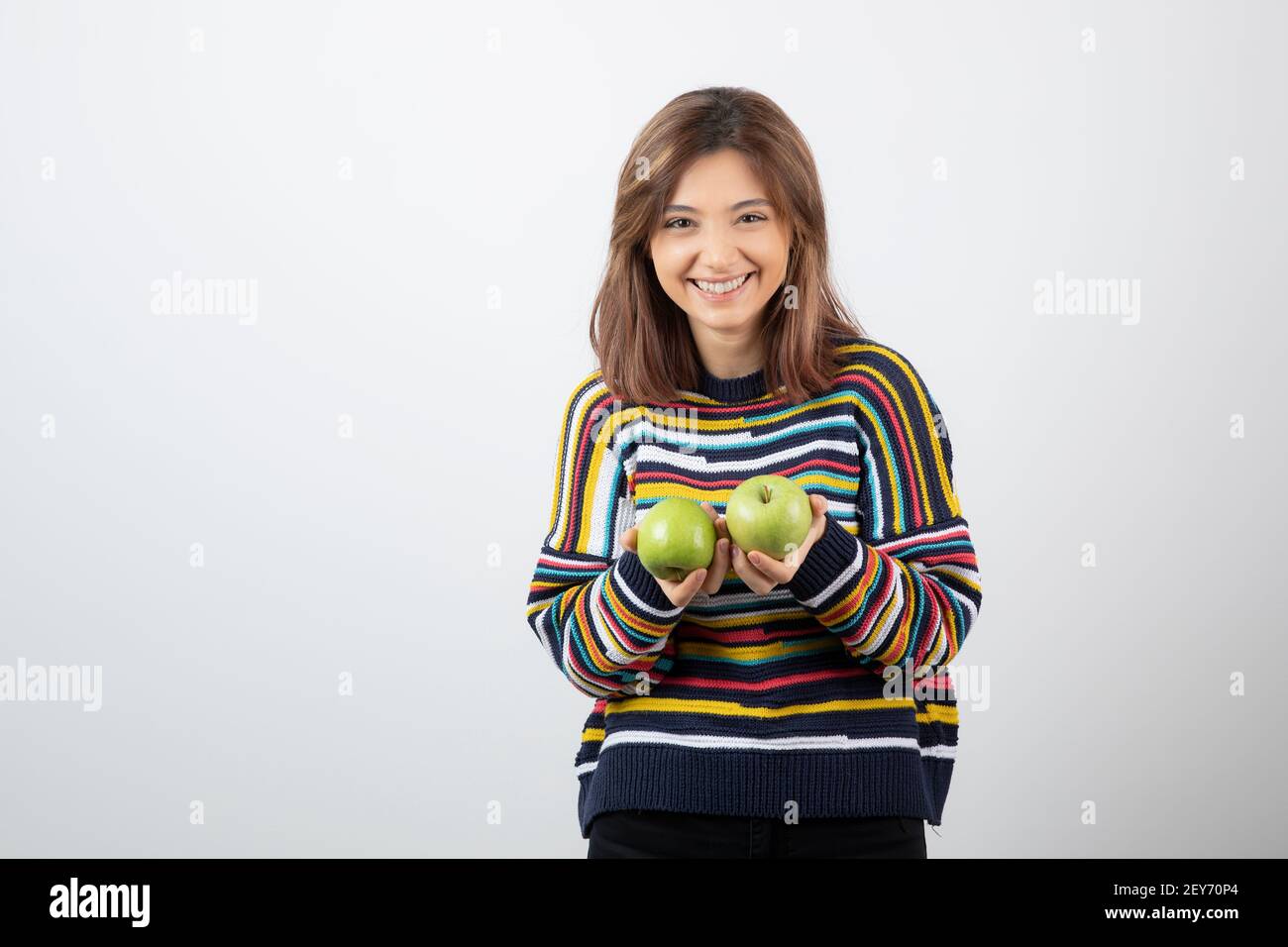 Junge Frau im lässigen Outfit hält grüne Äpfel mit einem Lächeln Ausdruck Stockfoto