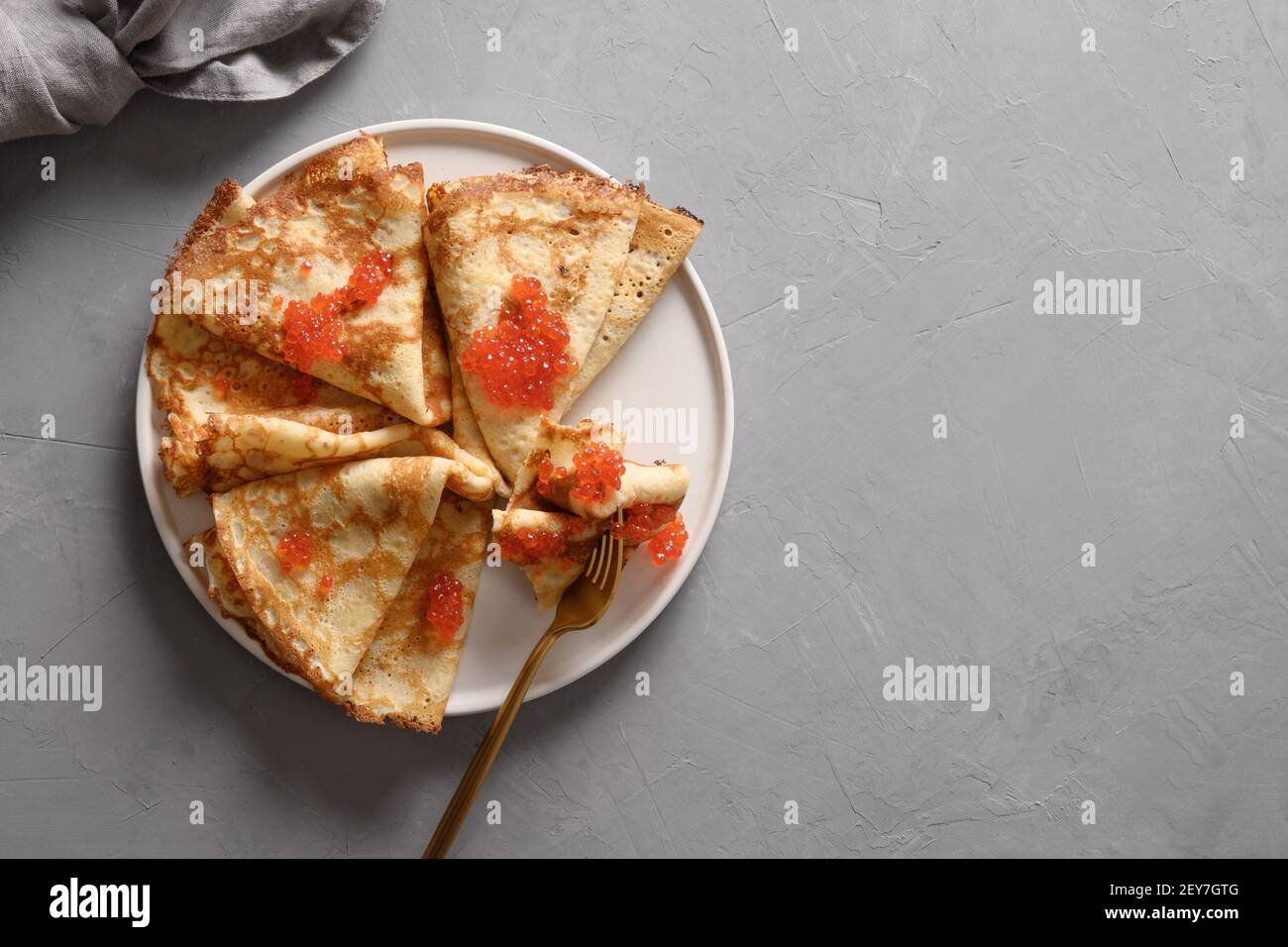Russische dünne Pfannkuchen oder Blini mit rotem Kaviar auf grauem Teller. Draufsicht. Pfannkuchen Woche. Fasching. Leerzeichen für Text. Stockfoto