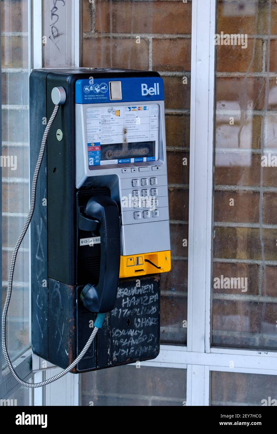 Ottawa, Ontario, Kanada - 6. Februar 2021: Ein abgenutztes Bell Canada Payphone mit Graffiti in einer schmutzigen Telefonzelle auf der Bank Street in Ottawa. Stockfoto