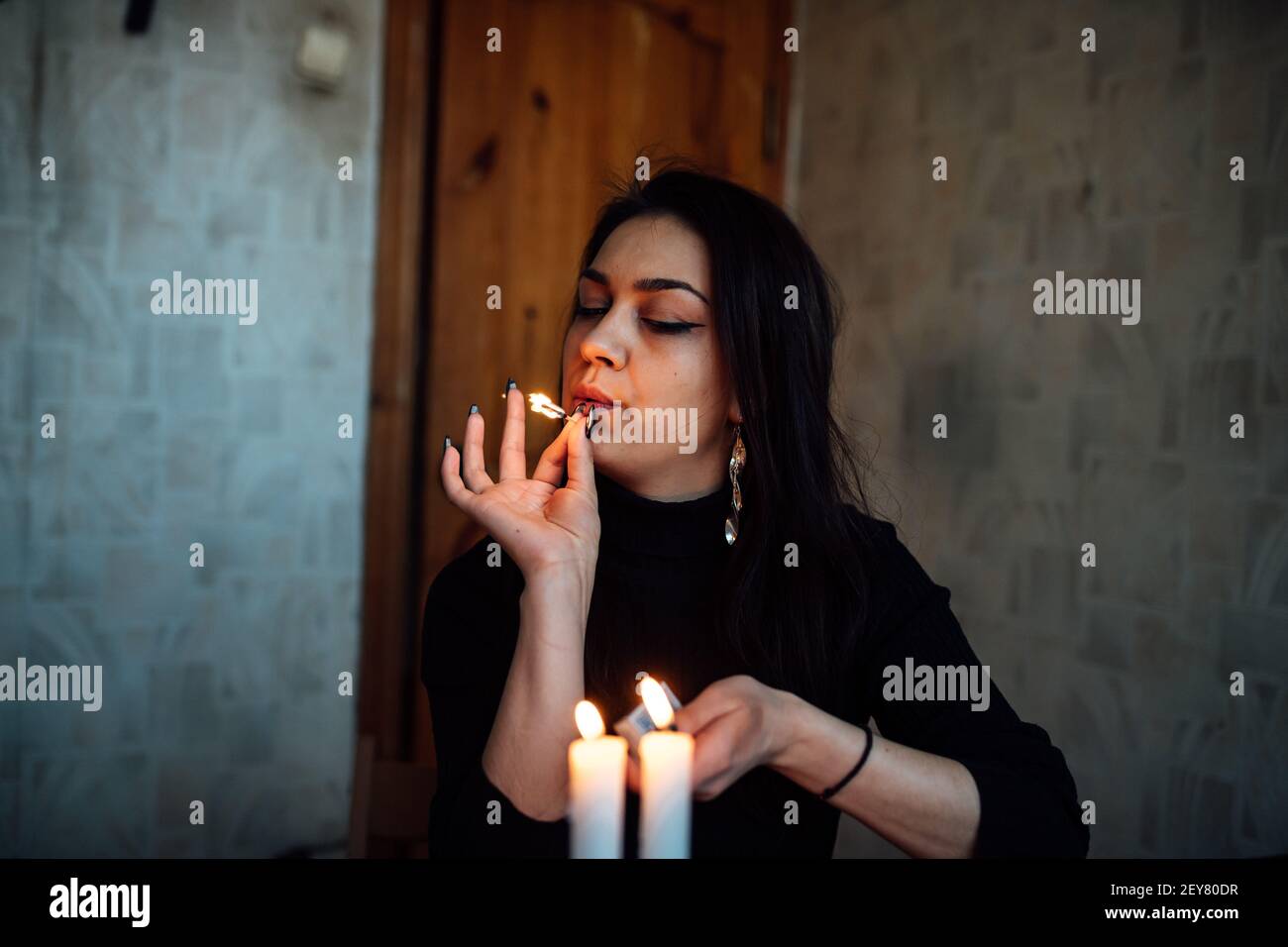 Ein Mädchen Wahrsager zündet Kerzen an, um die Zukunft vorherzusagen. Mystisches Ritual der Kommunikation mit Geistern Stockfoto