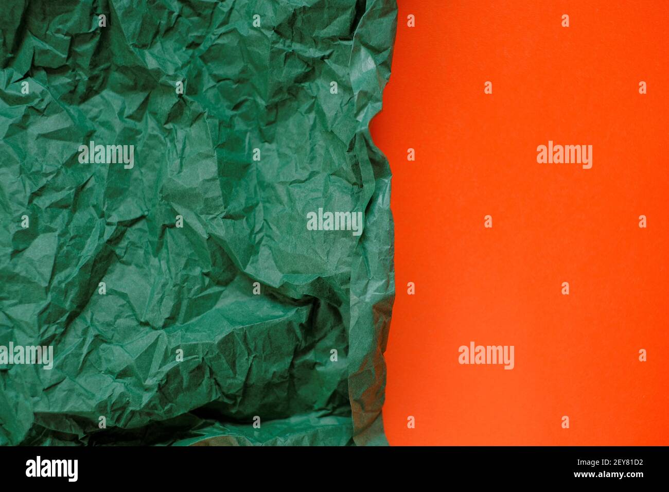 Leerer Papierhintergrund. Grün zerknittertes Papier auf einem orangen Hintergrund.Olive grün leeres Papier Hintergrund, Tapete, Platz für Text.Kreatives Papier Stockfoto