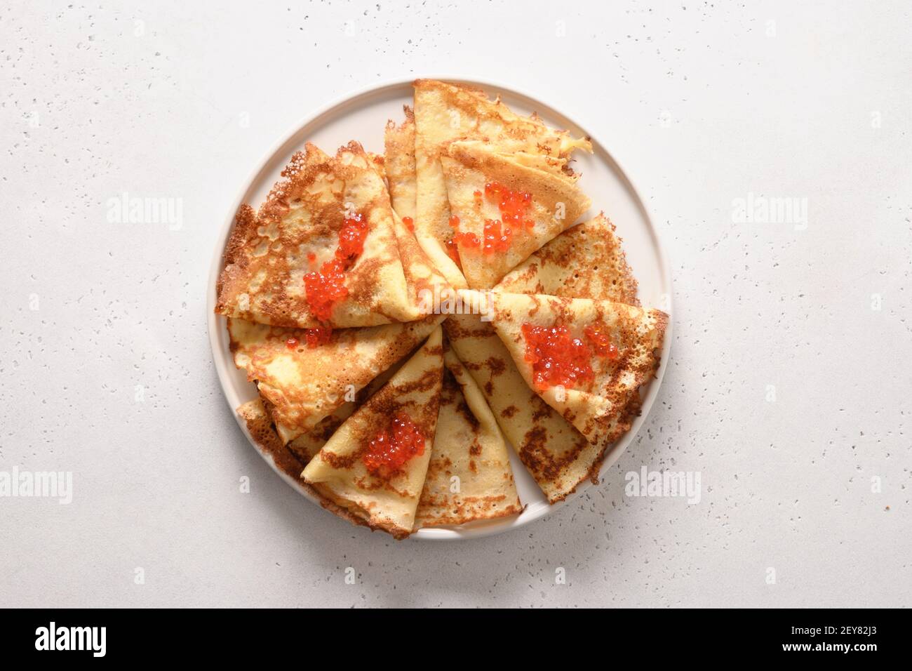 Dünne russische Pfannkuchen oder Blini mit rotem Kaviar auf Weiß. Stockfoto