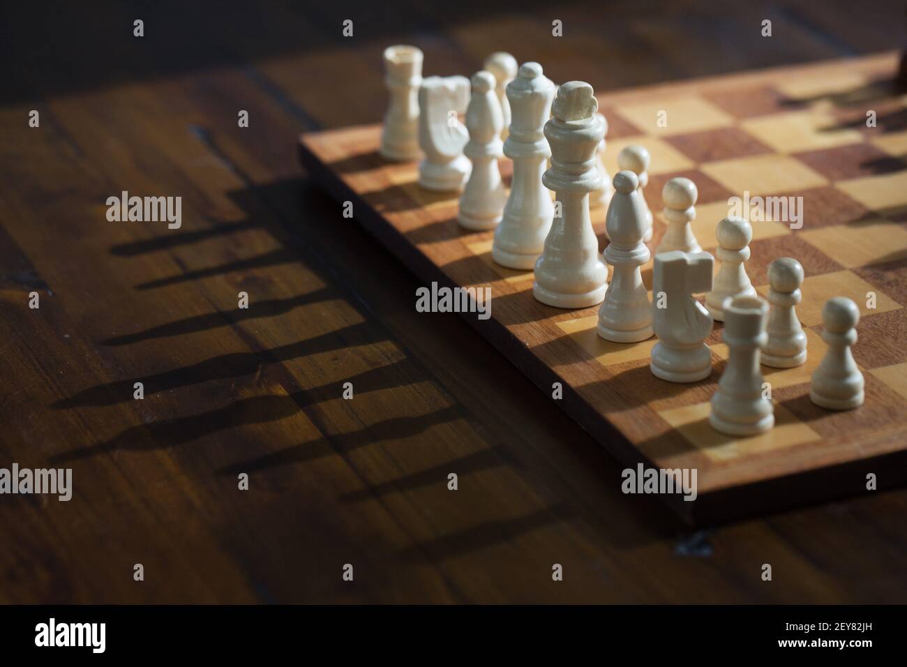 Schachfiguren auf einem Schachbrett werfen lange Schatten. Stockfoto