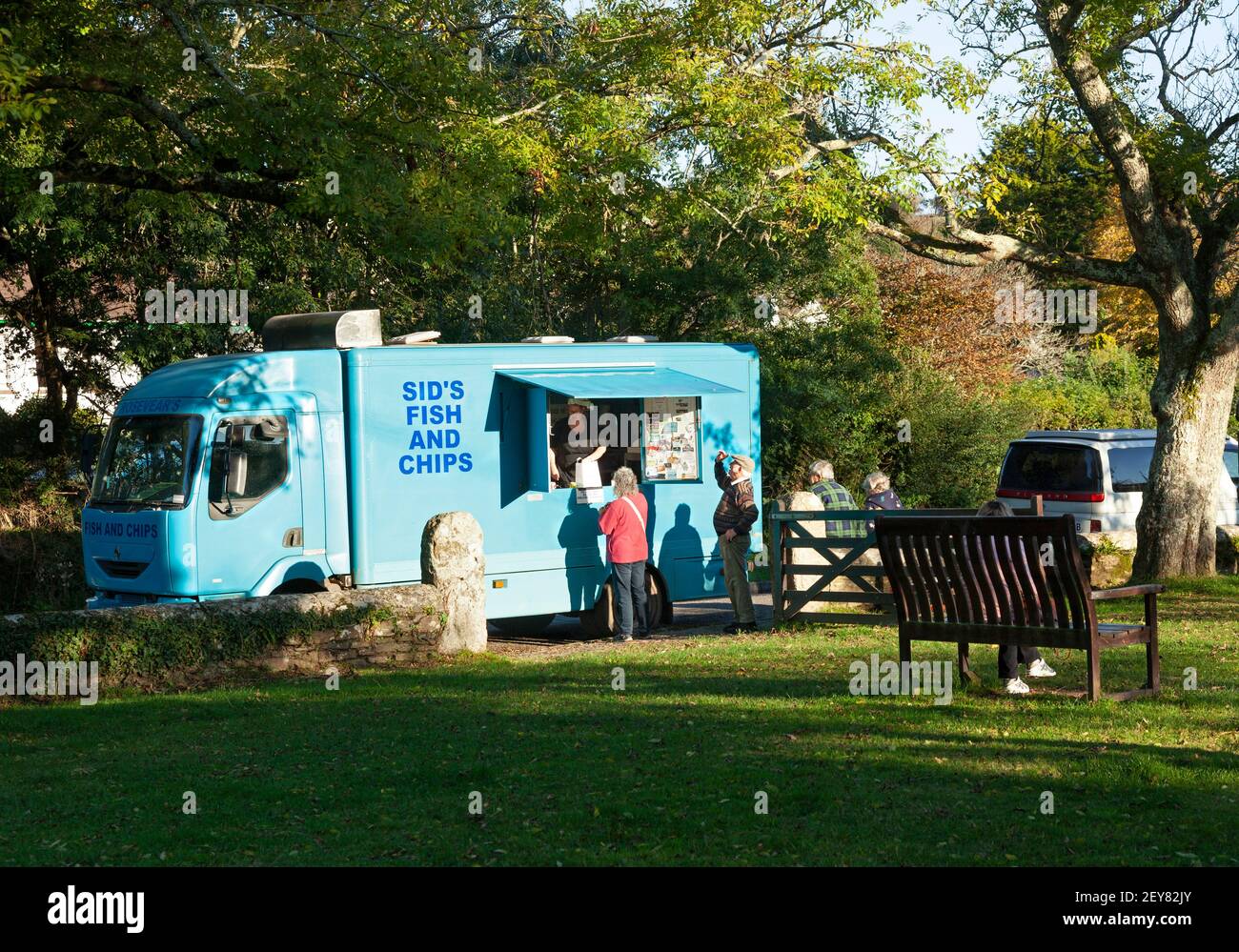 Ein Fisch-und-Chip-Van bedient eine Schlange von älteren Kunden im Dorfgrün von Gweek in Cornwall, Großbritannien Stockfoto